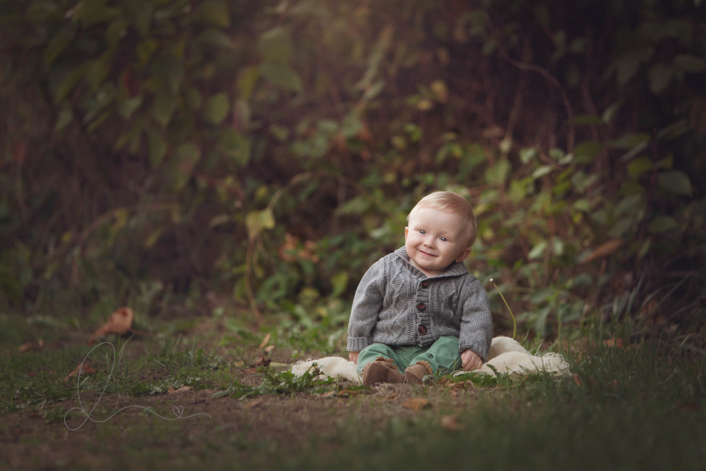 smiling baby boy sitting up outdoors